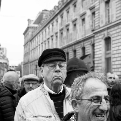 Black and white street photography of the french street photographer David Décamps representing a tall man with his eyes closed during a strike in Paris.