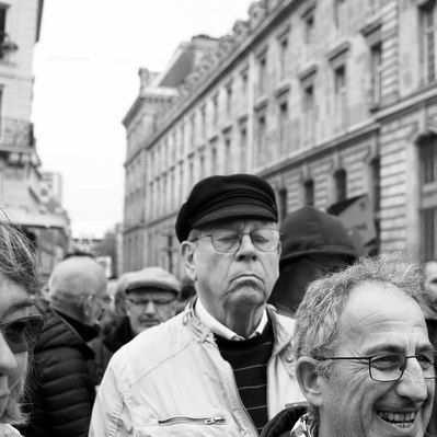 Black and white street photography of the french street photographer David Décamps representing a tall man with his eyes closed during a strike in Paris.