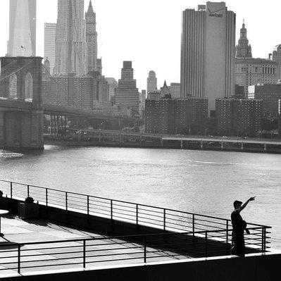 Black and white street photography of the french street photographer David Décamps representing a man with the skyline in New York City, USA.