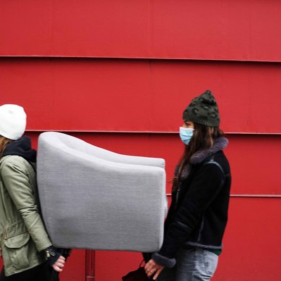 Street photography in colors of the french street photographer David Décamps representing two women moving an armchair in Paris.