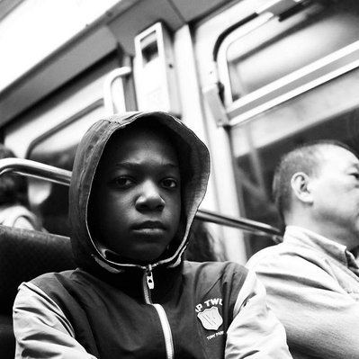 Black and white street photography of the french street photographer David Décamps representing a teenager with an intense look in Paris, France.