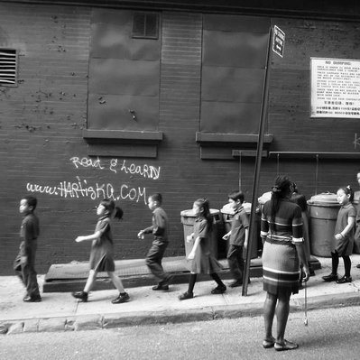 Black and white street photography of the french street photographer David Décamps representing a crowd of young students walking in the subway in Chinatown, New York City, USA.