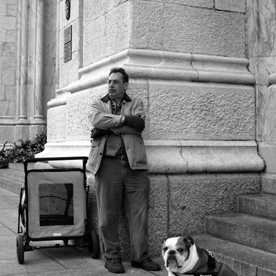 Black and white street photography of the french street photographer David Décamps representing a man with his dog in New York City, USA.