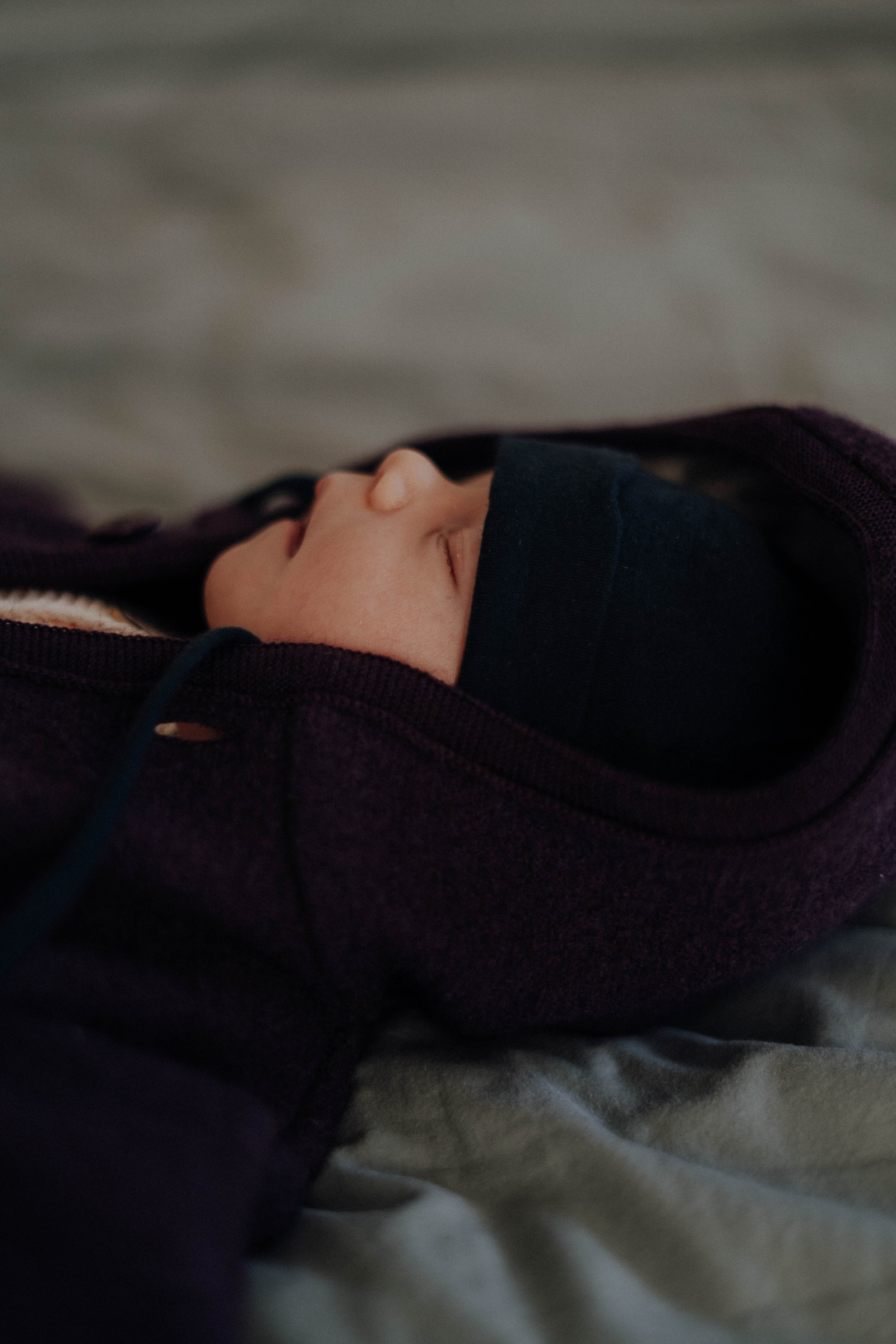 Angezogenes Winterbaby schläft auf dem Bett.
