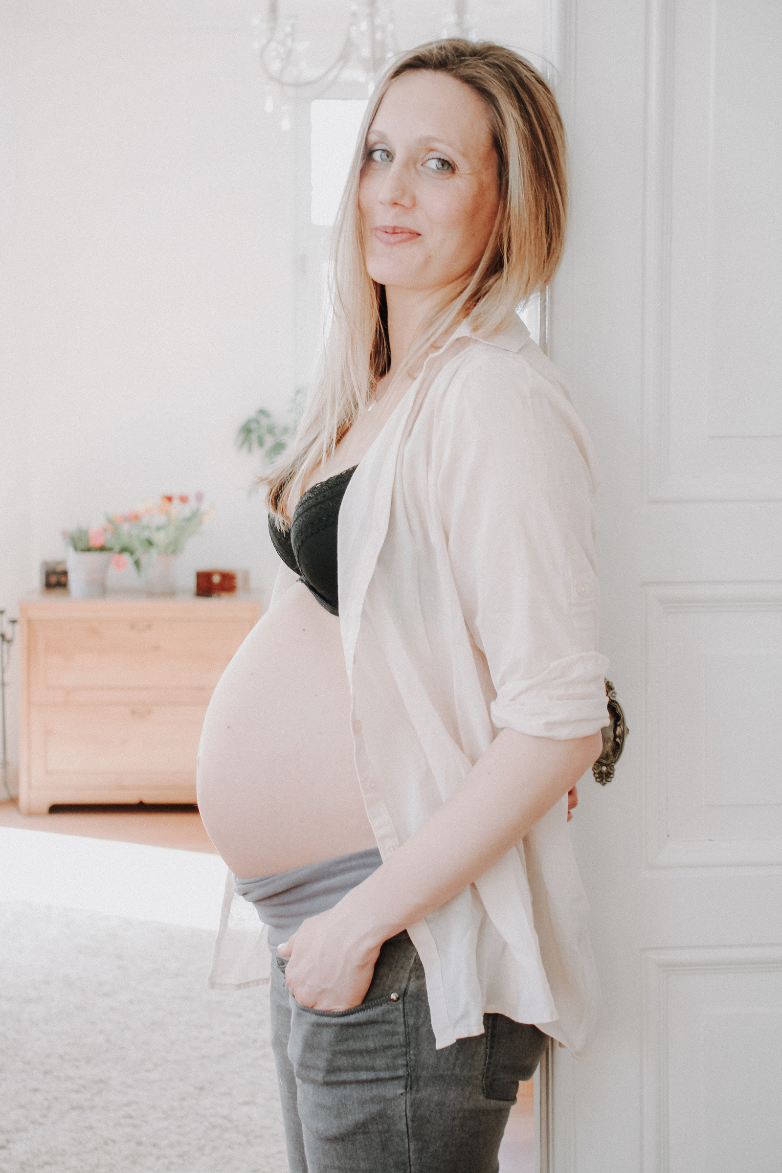 Schwangere Frau lehnt am Türrahmen. Natürliche Babybauchfotos in Kiel und Umgebung.