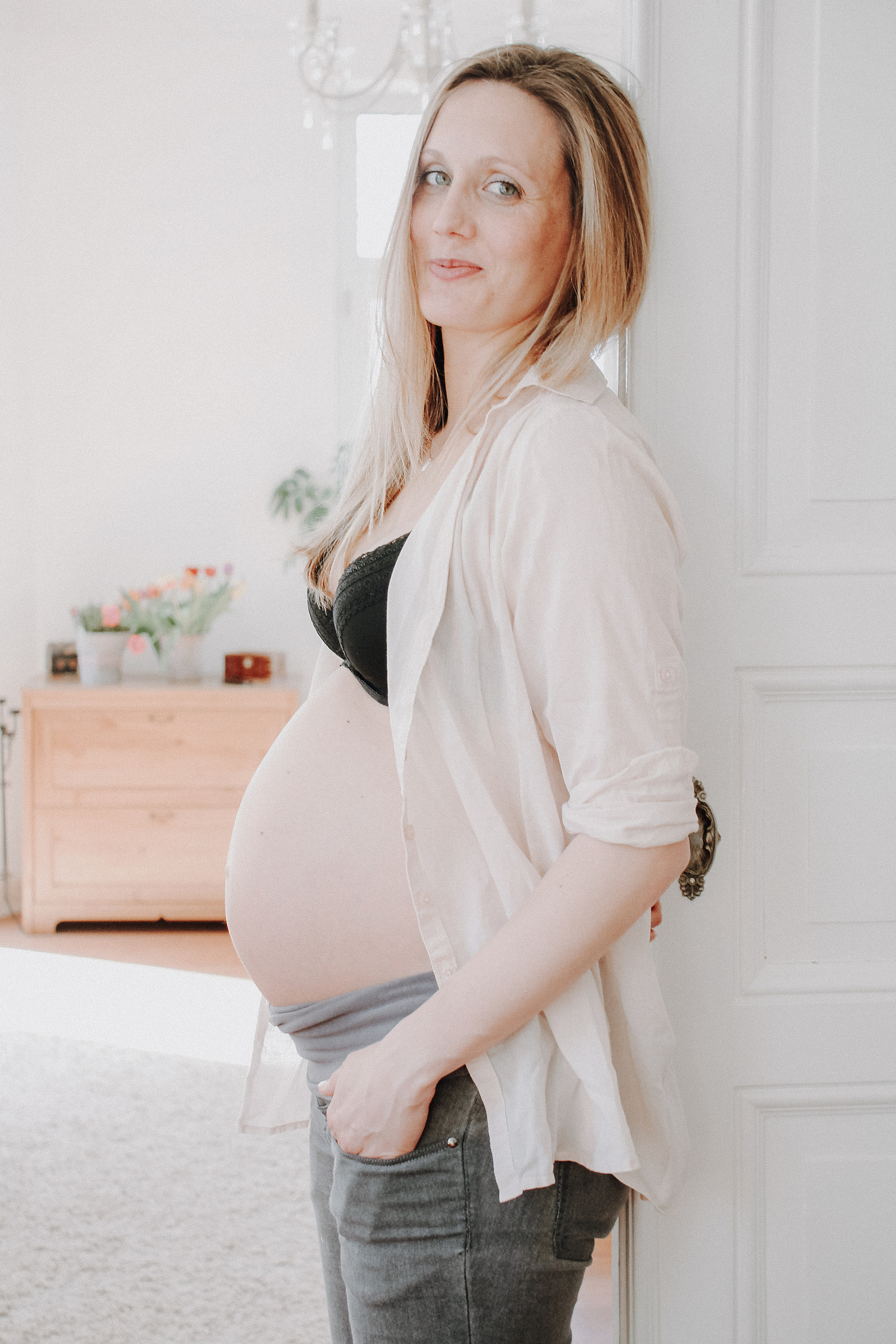 Schwangere Frau lehnt am Türrahmen. Natürliche Babybauchfotos in Kiel und Umgebung.