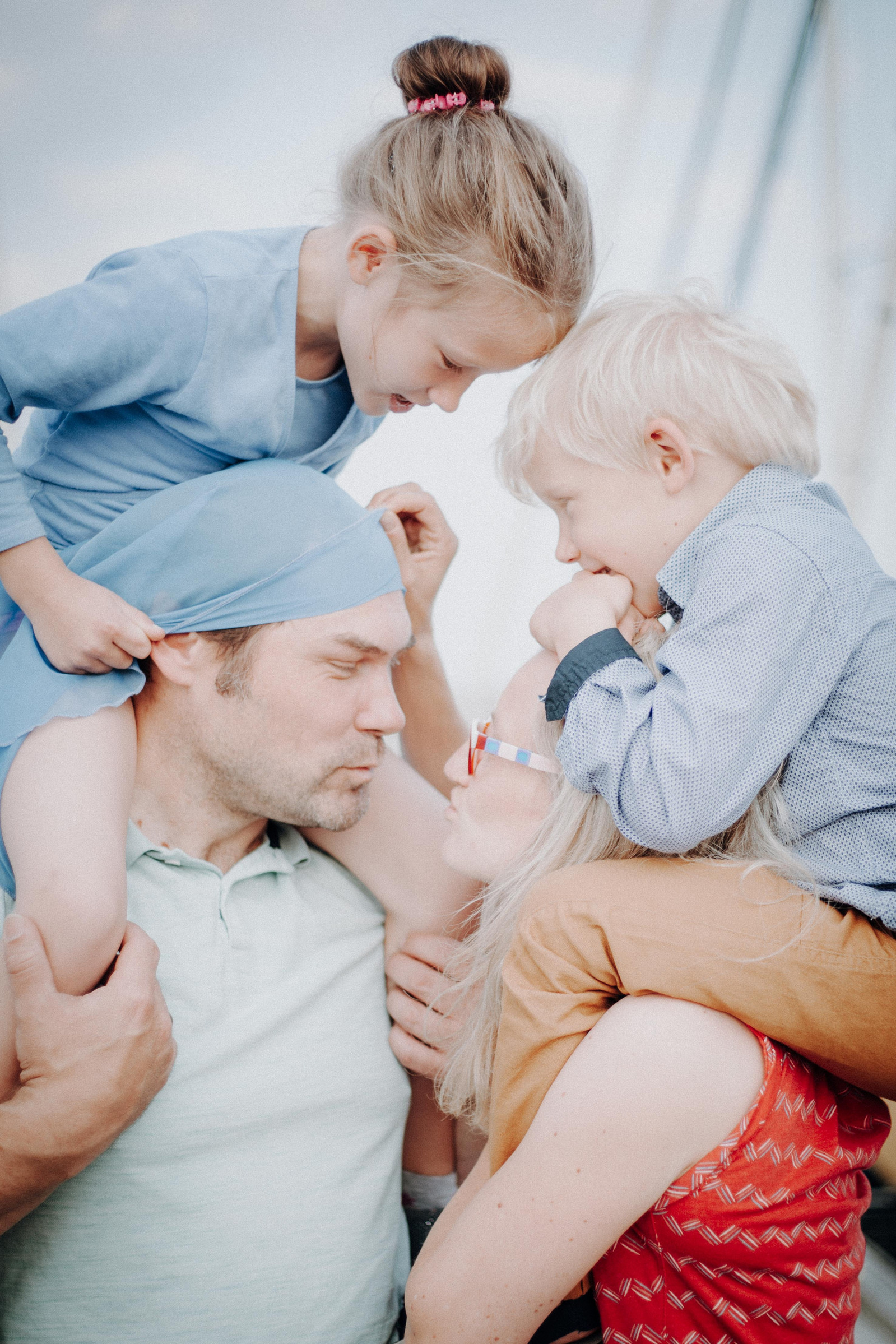 Familienportrait im Segelyachthafen Schilksee bei Kiel von Mutter und Vater, die Sohn und Tochter auf den Schultern haben und sich küssen.