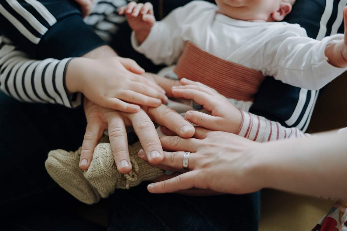 Neugeborenes Baby mit allen Händen der Familie im Vordergrund.