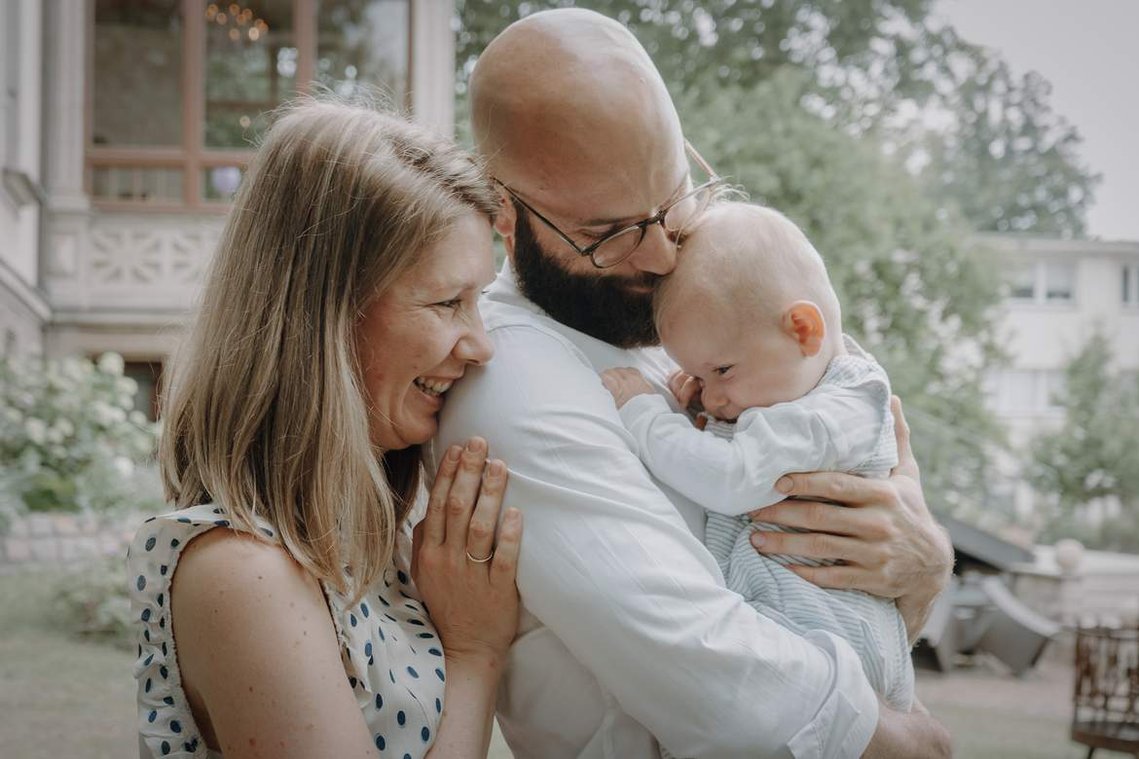 Junge Mutter und Vater halten Baby und kuscheln.