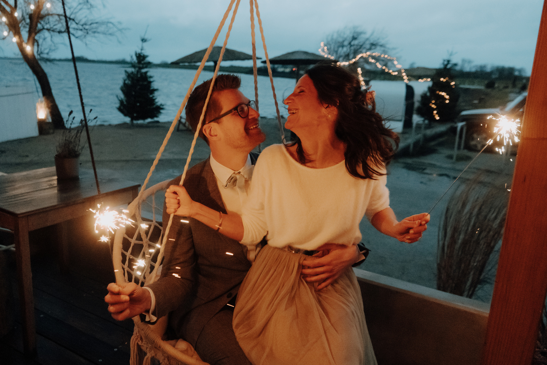 Hochzeitspaar schwingt in einem Hängesessel mit Wunderkerzen.