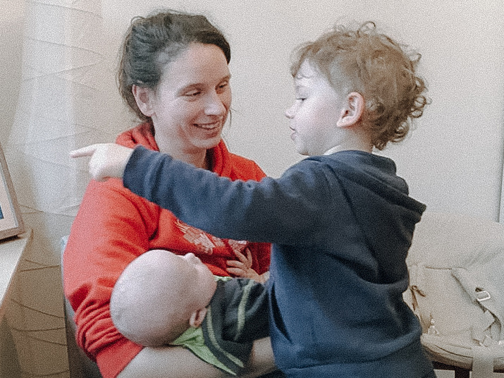 Junge Mutter mit zwei Kindern auf dem Schoß.