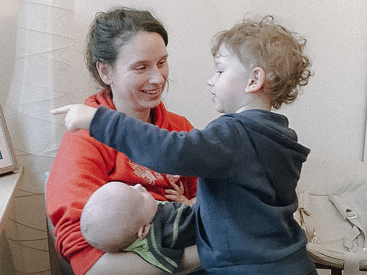 Junge Mutter mit zwei Kindern auf dem Schoß.