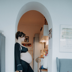 Schwangere Frau steht im Türrahmen.