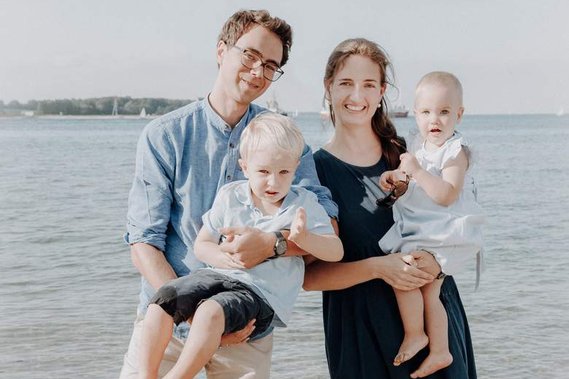 Familienfoto von Mama und Papa mit Baby und Kleinkind am Strand in Kiel.