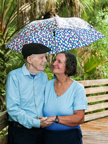 An older married couple stand under an umbrella during the rain in Florida. 