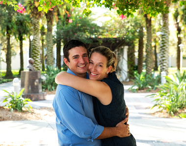 A young couple hugs underneath an arbor
