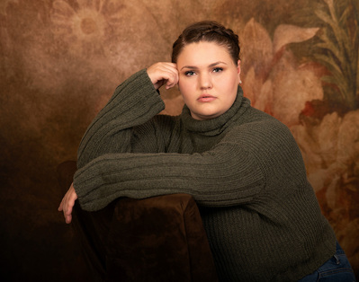 Portrait of a woman sitting in front of a floral background.  
Williamsburg, VA Photographer