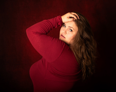 Low-key portrait of a woman on a red background.  
Williamsburg, VA Photographer