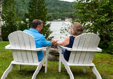 A couple sit in  lawn chairs by the water in Vermont