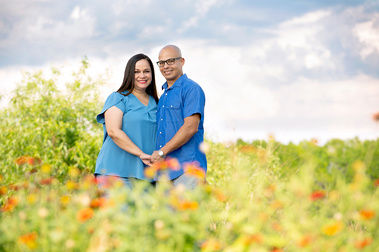 A young hispanic couple stand together with flowers in the foreground in Tampa, FL