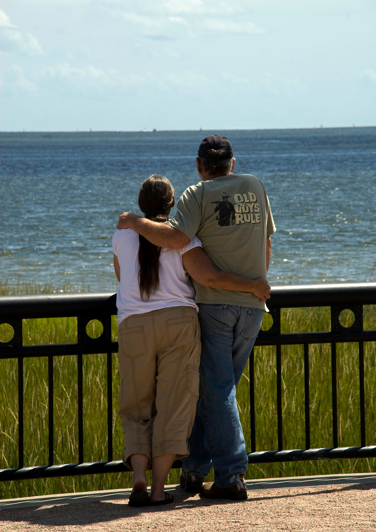 An older couple on vacation standing together looking at the water in Charleston, SC