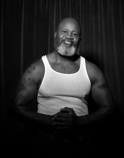 An African American man with a  beard poses for a black and white portrait for The Man Project