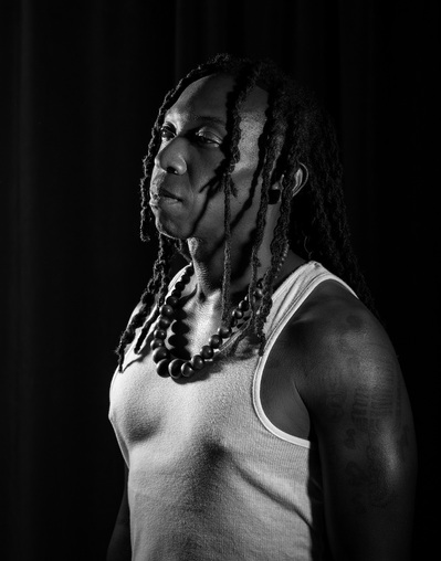 A black man with dreads poses for a black and white portrait for a photo project by Williamsburg, VA photographer Dark Light Portrait Studios
