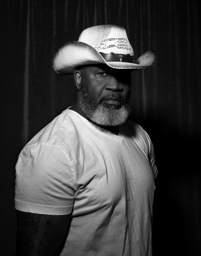 A man poses in a cowboy hat for a black and white portrait by Williamsburg, Virginia photographer Dark Light Portrait Studios
