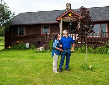 A couple stands in front of their house in Vermont