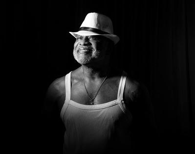 A man poses wearing a white hat in a black and white portrait by Dark Light Portrait Studios of Williamsburg, VA