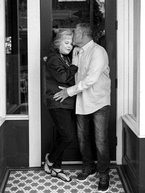 A married couple stand in a doorway in a black and white photograph 