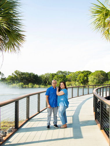 A hispanic couple stand on a walkway by the water in Tampa, FL
