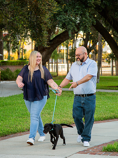 A couple walks their puppy in the park