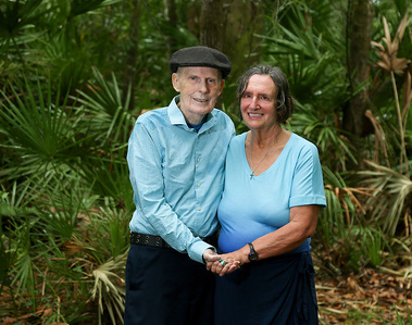 An older married couple stand together outside in Florida