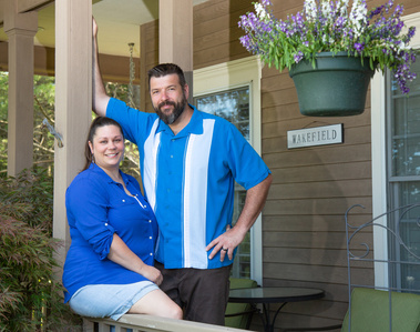 A couple stands on the porch of their house