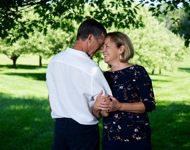 A married couple look into each others eyes in Vermont under a tree canopy