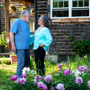 A married couple look at each other outside their house in Vermont