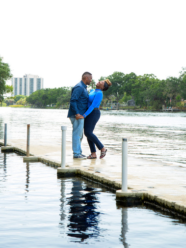 A married couple laugh on a pier in the water