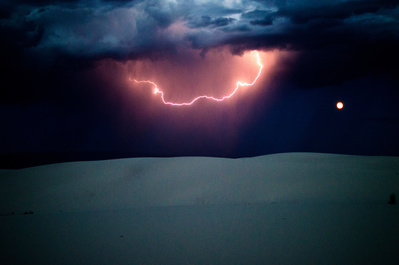 Four days after man-made fireworks dotted the sky, nature provided a luminous grandeur over White Sands National Monument, Saturday, July 8, 2017, with a full moon and a cloud-to-cloud lightning strike. Photo by Anthony Albidrez (Las Cruces Bulletin)