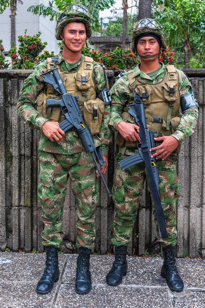 Two young male soldiers with their machine guns posing in Medellin, Colombia  