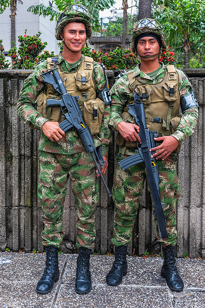Two young male soldiers with their machine guns posing in Medellin, Colombia  