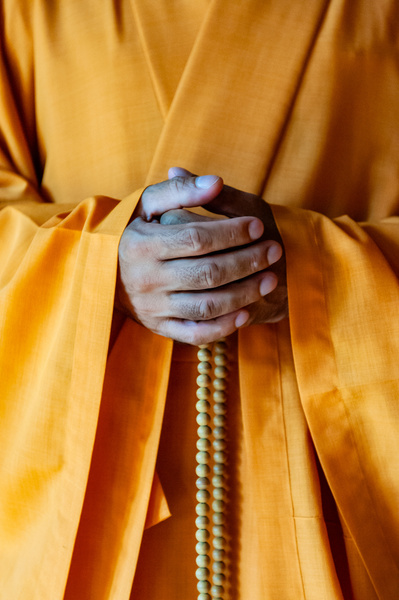 The meditative pose of a Buddhist monk holding his mala prayer beads