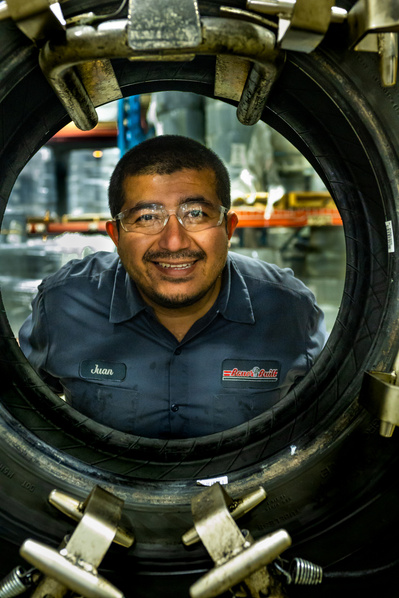 Male equipment operator posing and smiling inside a tire at a truck maintenance facility