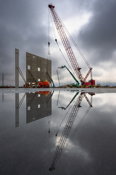 Crane lifting large concrete building panel being artfully reflected in water seen by a Chicago commercial photographer