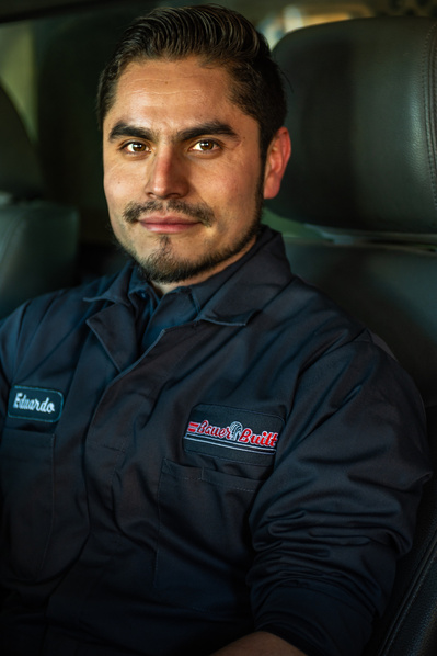 Corporate photographer view of a male machinist posing and smiling at a truck maintenance facility for truck wheel and tire repairs