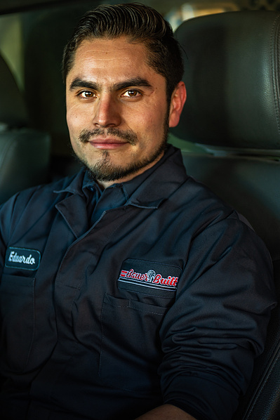 Corporate photographer view of a male machinist posing and smiling at a truck maintenance facility for truck wheel and tire repairs