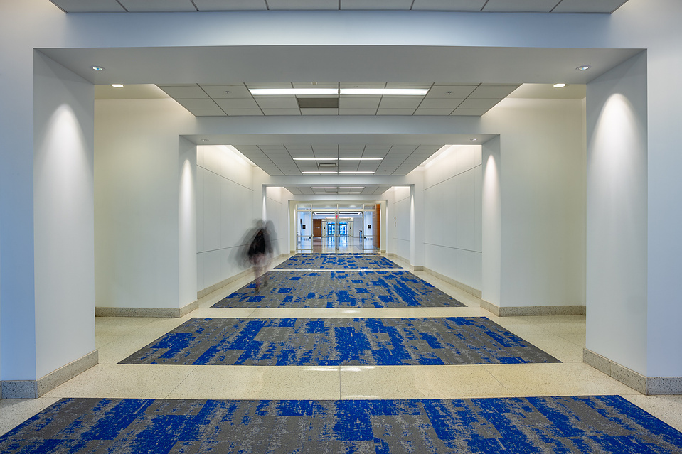 Person walking down a long hallway in a large corporate office building