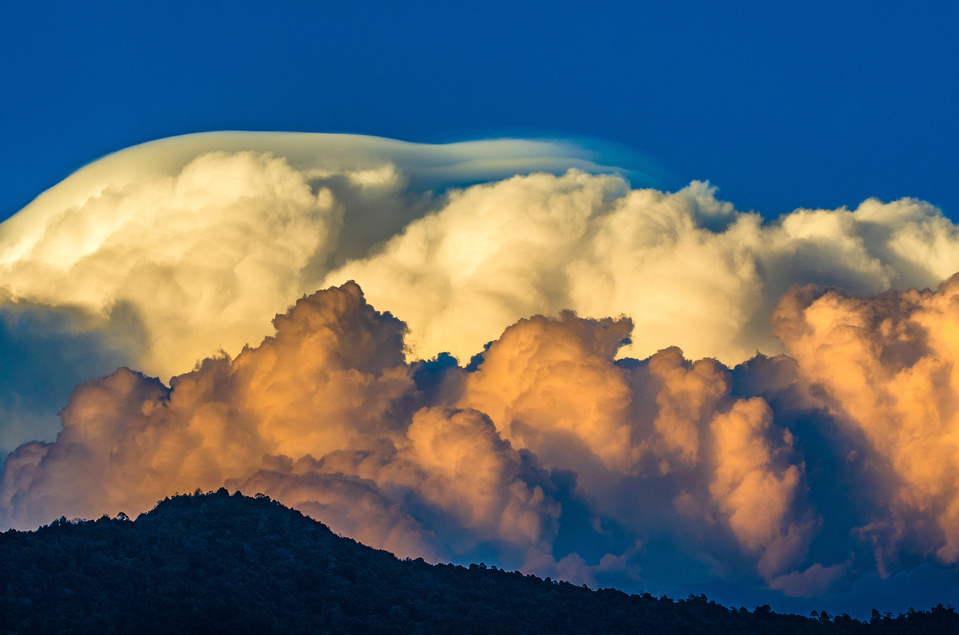 Colorful and otherworldly looking puffy clouds over a mountain range