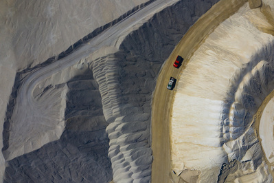 Aerial view of two trucks driving on a road through a gravel quarry