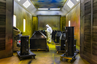 Product photographer captured a commercial painter in a paint room with painted parts in a commercial coffee roaster manufacturing facility